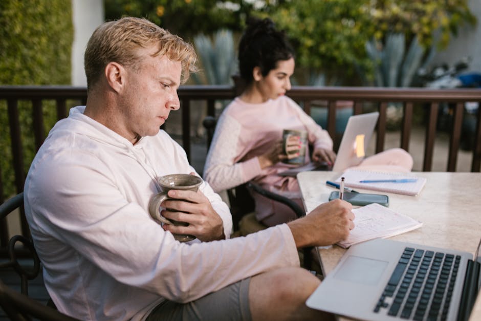 A couple working together on their laptops while enjoying a coffee outdoors